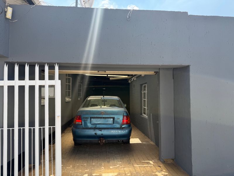 A single garage space featuring a paved driveway and secure gated entrance, finished with grey painted brickwork.