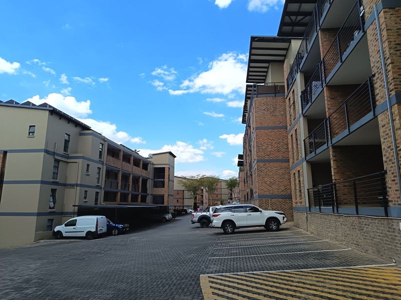 Exterior view of a modern apartment complex featuring brick facades, paved parking areas, and private balconies.