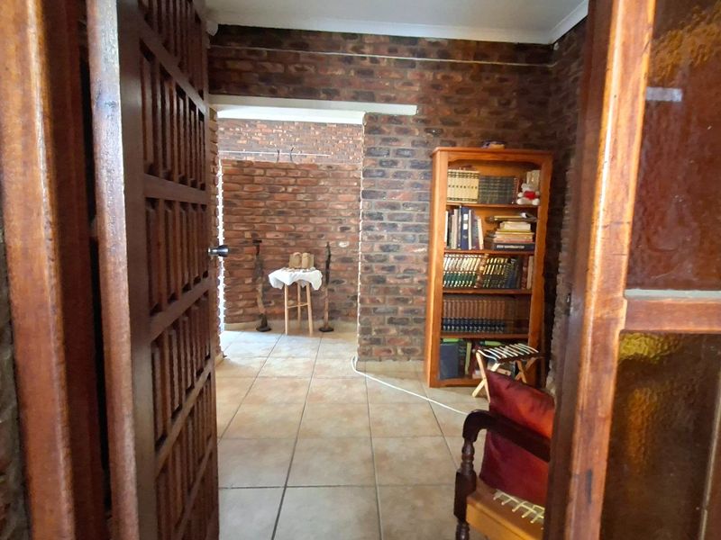 A hallway featuring rustic exposed brick walls and ceramic floor tiling, providing a warm and textured transition between living spaces.