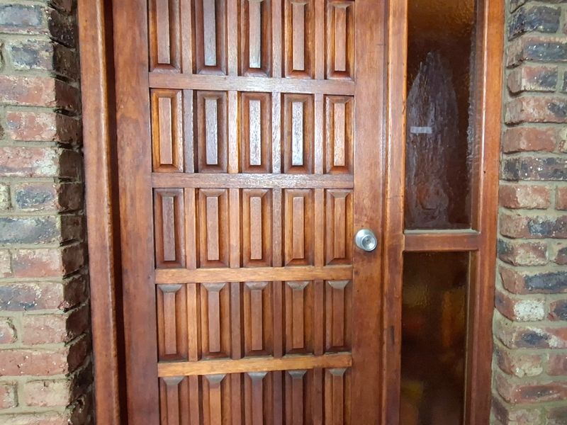 A traditional timber panelled entrance door featuring a side glass panel, set within a rustic face brick exterior wall.
