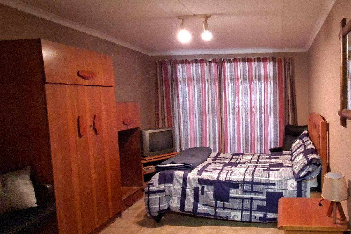 A functional bedroom featuring tiled flooring, ceiling coving, and track lighting, providing a comfortable and practical living space.