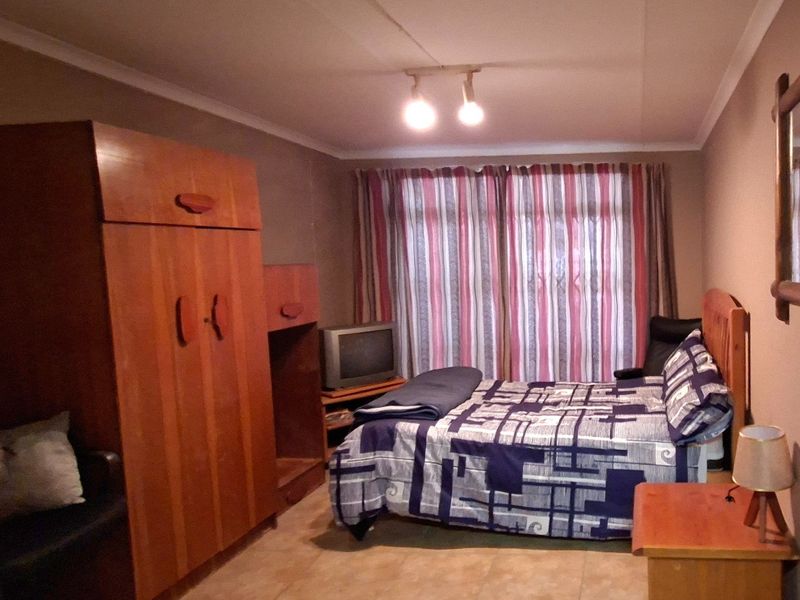 A functional bedroom featuring tiled flooring, ceiling coving, and track lighting, providing a comfortable and practical living space.