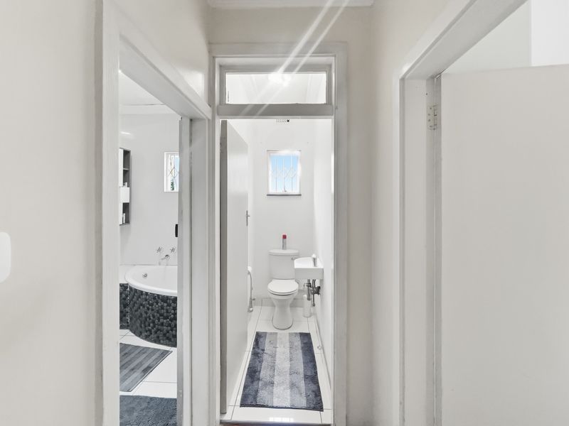 A view from the hallway looking into a bathroom and separate toilet area featuring tiled floors and functional sanitary fixtures.