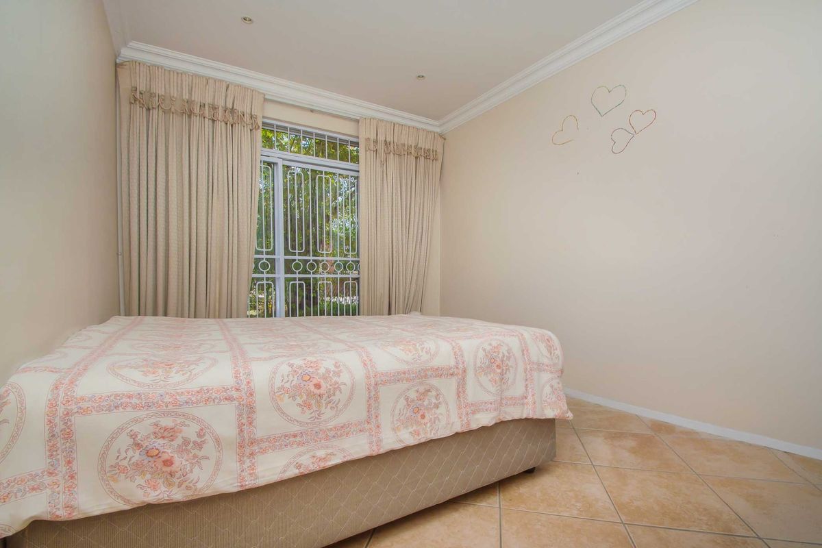 A bedroom featuring tiled flooring, recessed lighting, and a window fitted with a security gate.