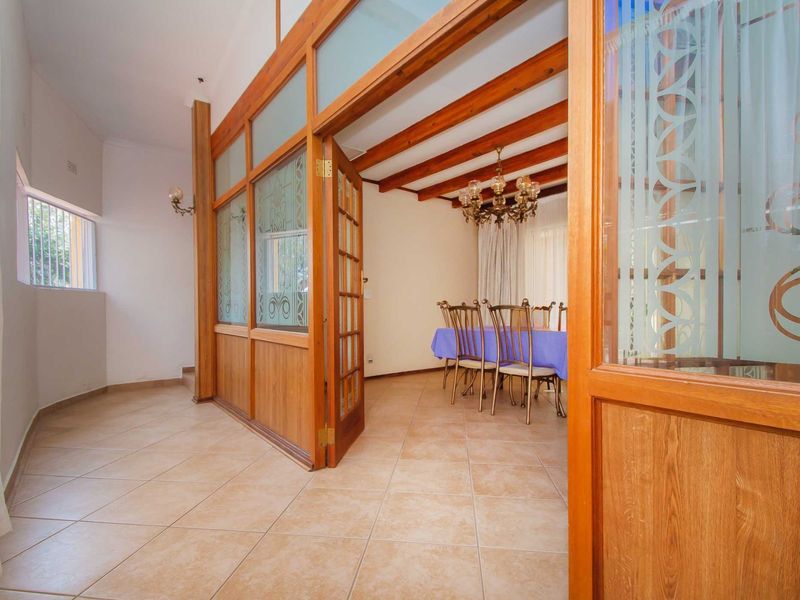 Dining room featuring exposed timber ceiling beams, ceramic floor tiling, and a decorative timber-framed glass partition wall.