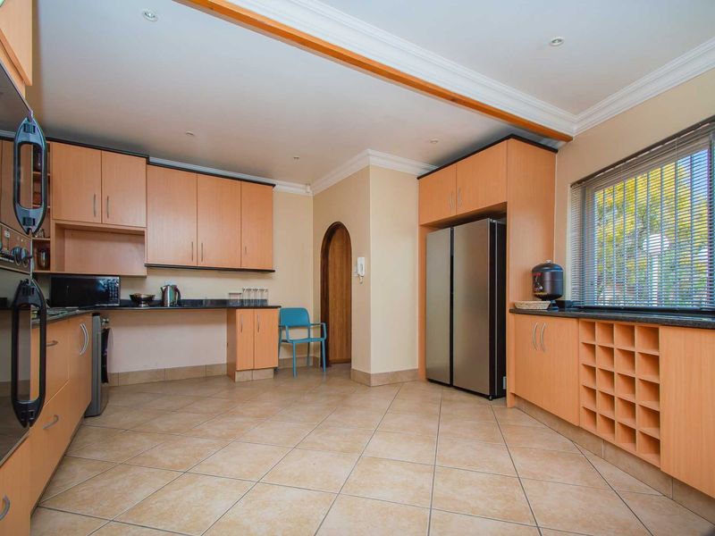 A functional kitchen featuring light wood cabinetry, granite countertops, built-in oven, and tiled flooring with a dedicated wine storage rack.
