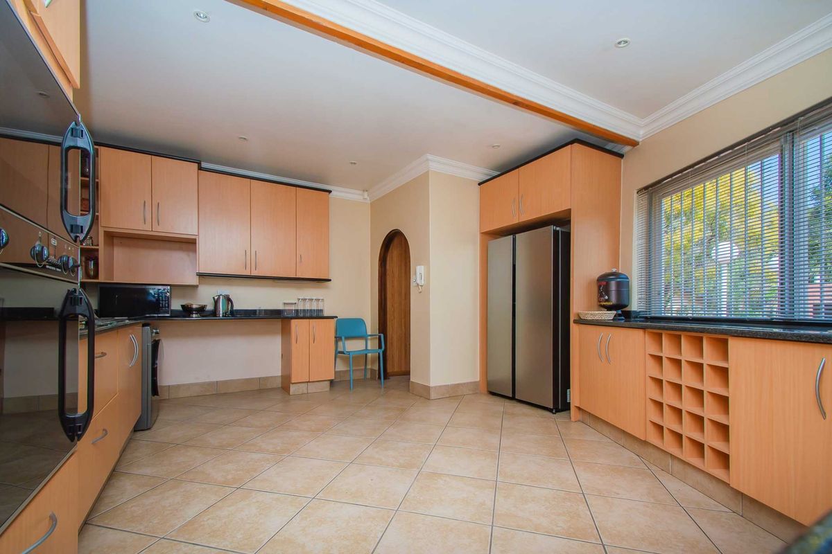 A functional kitchen featuring light wood cabinetry, granite countertops, built-in oven, and tiled flooring with a dedicated wine storage rack.
