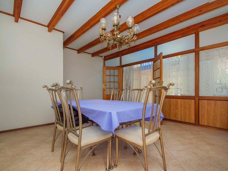 Dining room featuring exposed timber ceiling beams, tiled flooring, and a distinctive timber-framed glass partition wall with decorative glass panels.