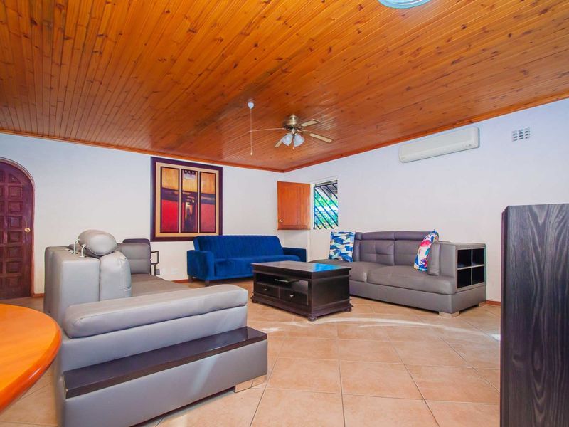 Spacious living room featuring a warm timber-clad ceiling, tiled flooring, and a split-system air conditioner for climate control.
