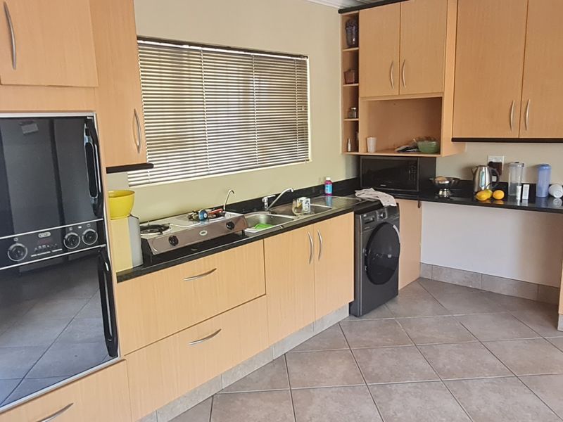 Functional kitchen featuring light wood cabinetry, granite countertops, built-in oven, gas hob, and tiled flooring with ample storage space.