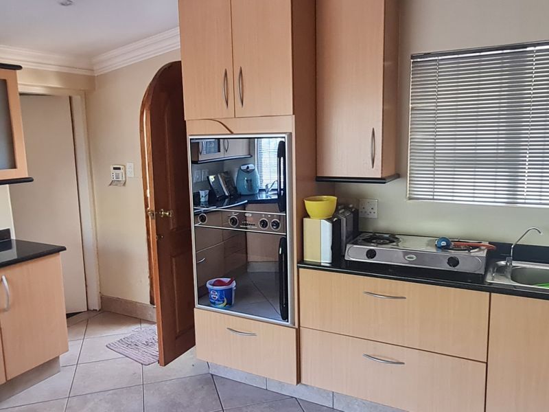 A functional kitchen featuring light wood cabinetry, granite countertops, a built-in oven, gas hob, and tiled flooring with a window for natural light.