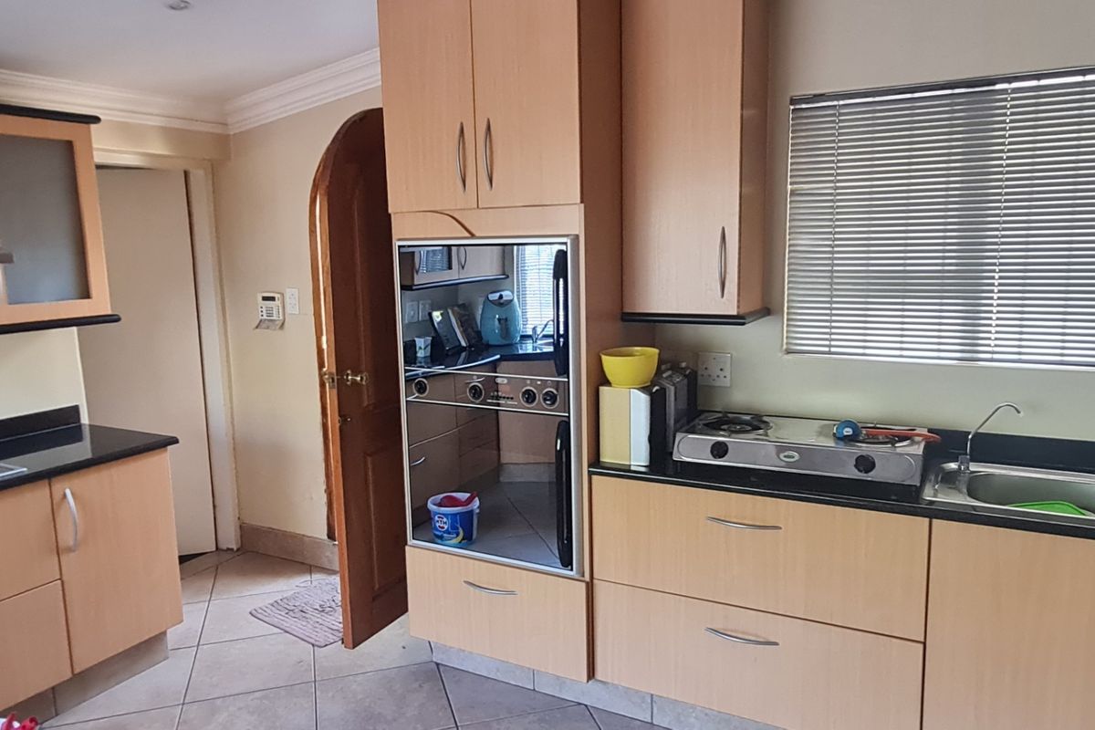 A functional kitchen featuring light wood cabinetry, granite countertops, a built-in oven, gas hob, and tiled flooring with a window for natural light.