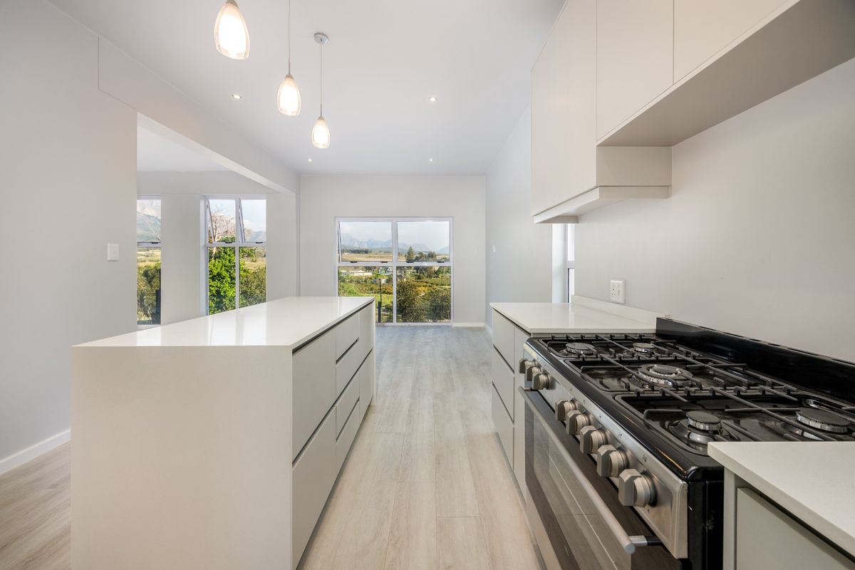 Modern kitchen featuring a central island, quartz countertops, gas stove, and sleek cabinetry, complemented by bright recessed lighting and scenic mountain views.
