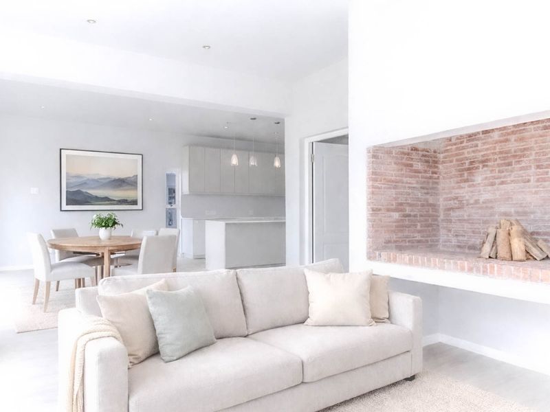 Bright open-plan living area featuring a modern kitchen with island and a distinctive exposed brick fireplace, creating a seamless and airy living space.