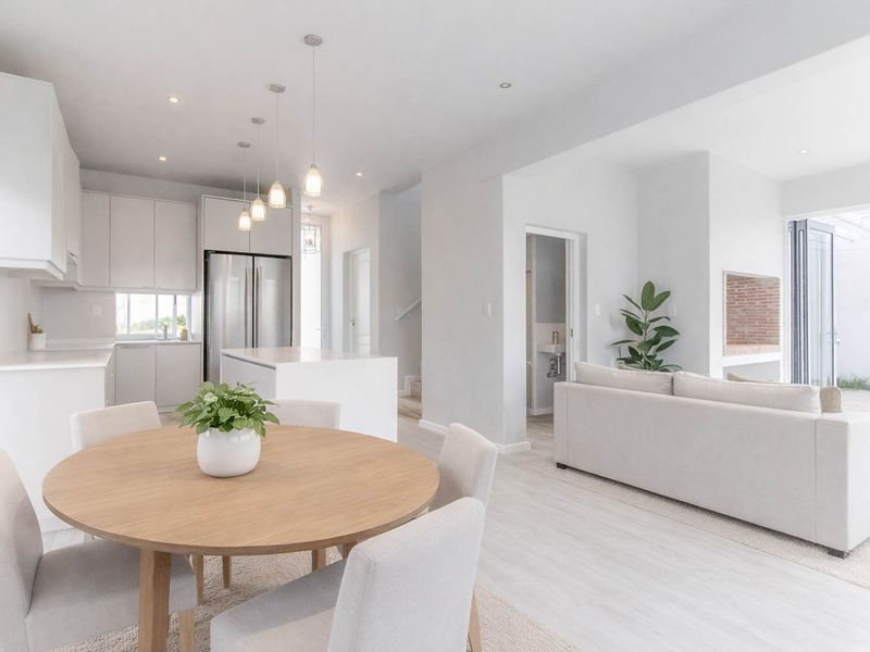 Modern open-plan living area featuring a sleek kitchen with island, dining space, and seamless flow to an outdoor patio through bi-fold doors.