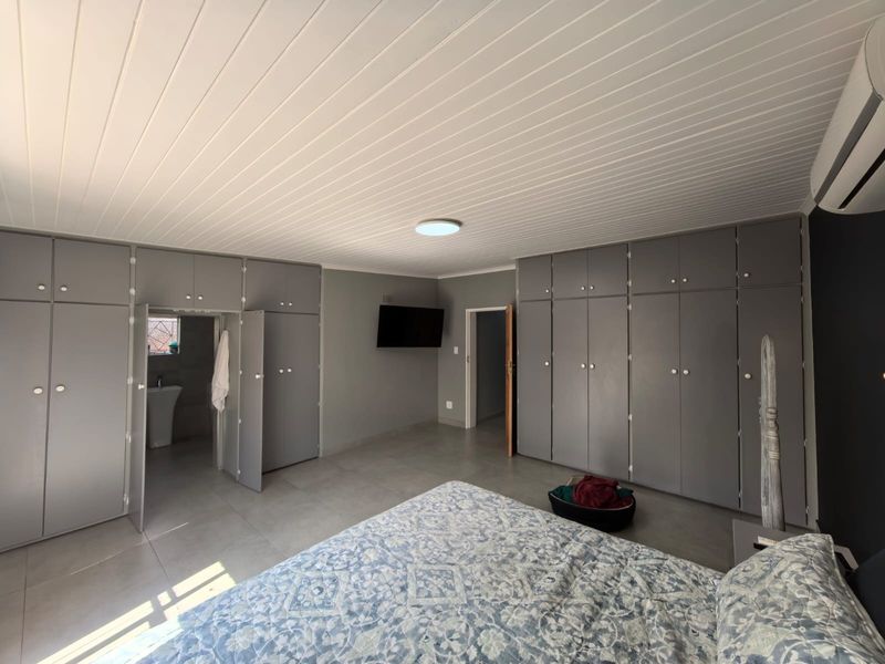 Spacious bedroom featuring extensive built-in cabinetry, tiled flooring, a modern tongue and groove ceiling, and an integrated air conditioning unit.