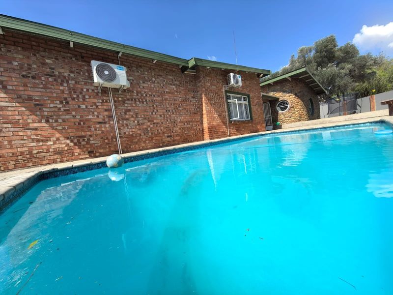 A view of the swimming pool area featuring a brick exterior facade and mounted air conditioning units.