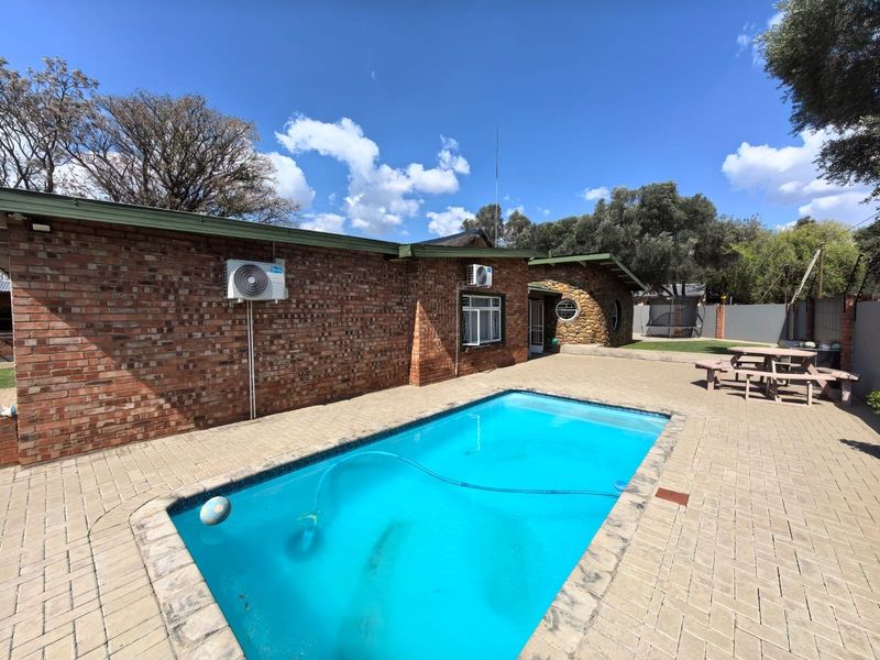 A well-maintained outdoor pool area featuring brick paving, a face brick exterior, and stone cladding accents, providing a functional space for recreation.