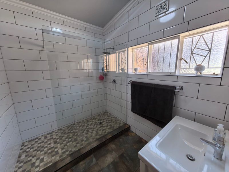 Modern bathroom featuring a spacious walk-in shower with glass screen, subway wall tiling, mosaic floor accents, and a clean vanity basin.