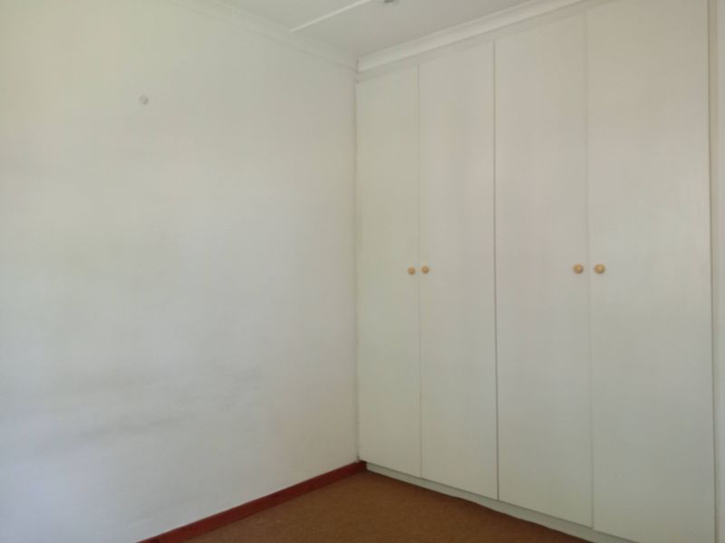 An empty bedroom featuring built-in cupboards, carpeted flooring, and coved ceilings, offering a blank canvas for personalization.