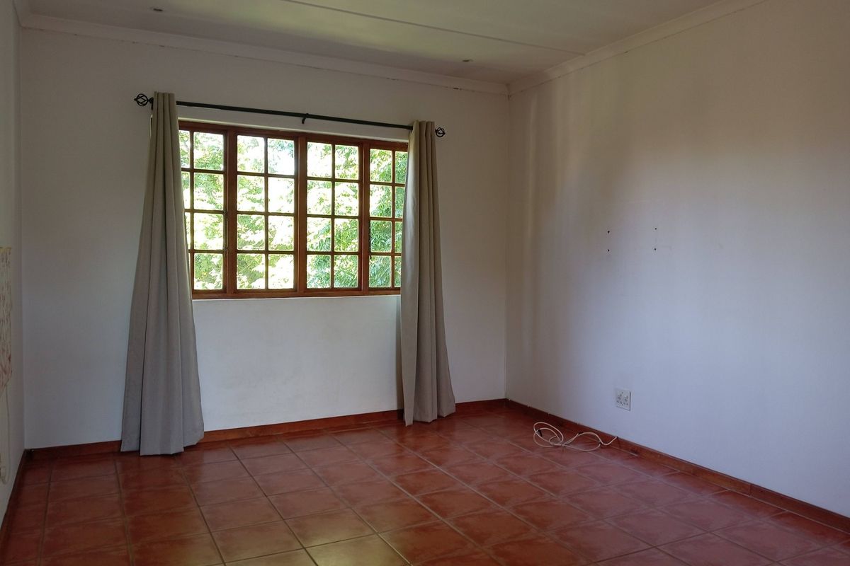A vacant bedroom featuring tiled flooring and a wooden window frame, offering a blank canvas for personalization.