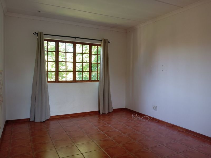 A vacant bedroom featuring tiled flooring and a wooden window frame, offering a blank canvas for personalization.