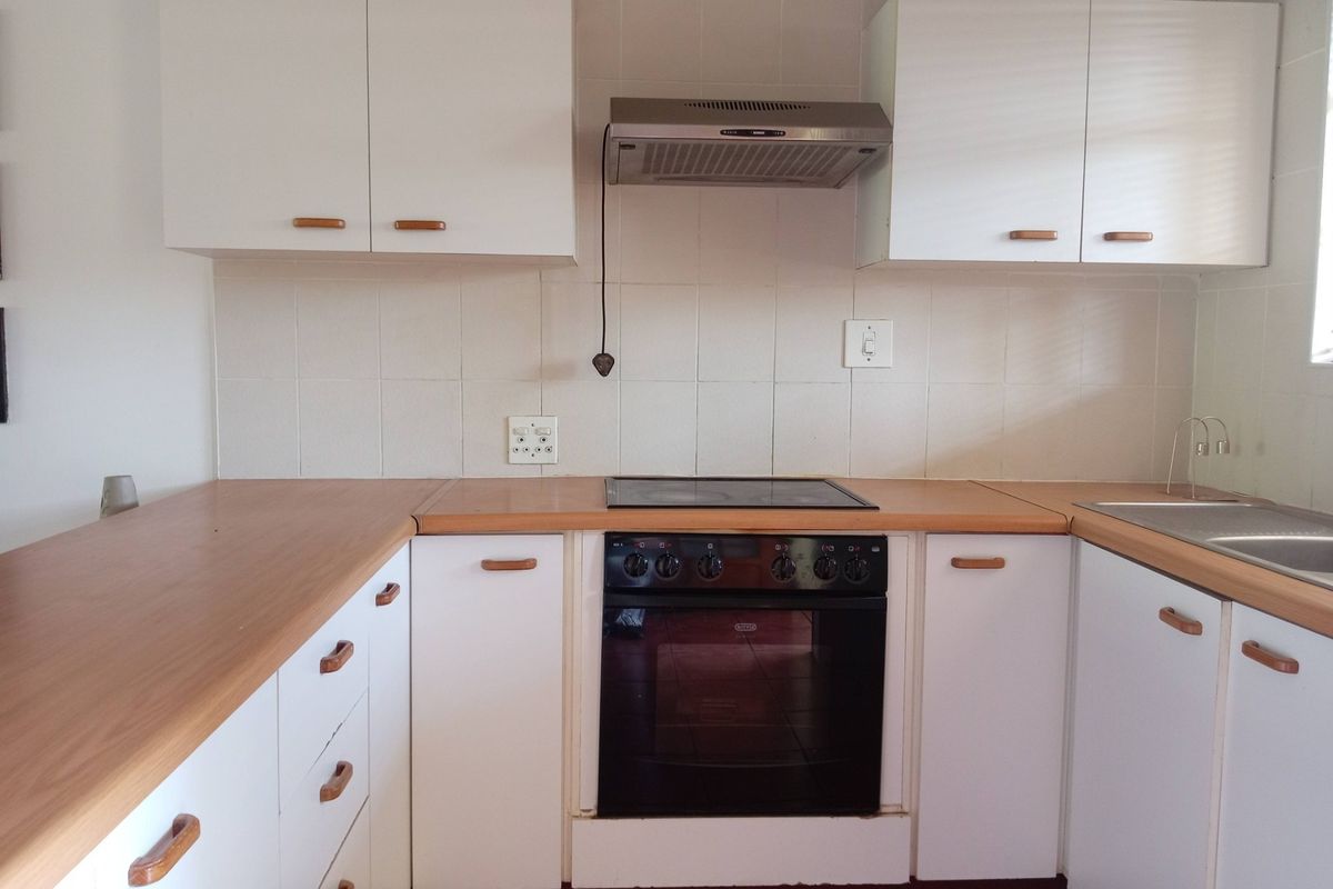 A functional kitchen featuring white cabinetry, laminate countertops, a built-in oven with electric hob, and a tiled backsplash.
