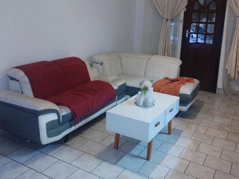 A living room area featuring tiled flooring and a traditional timber entrance door.