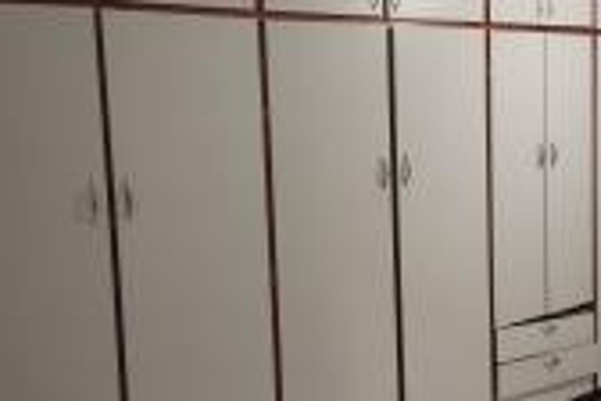 A bedroom featuring extensive built-in cupboards with overhead storage and integrated drawers, providing ample storage space.