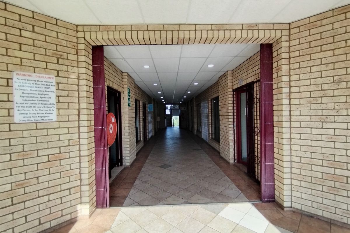 A long, tiled hallway featuring exposed brick walls and recessed ceiling lighting, providing access to multiple entry points.