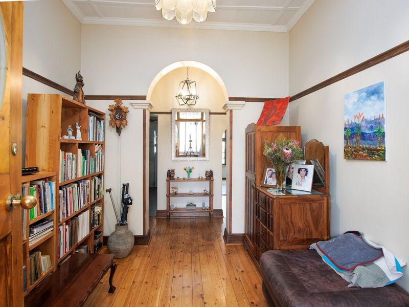 A character-filled hallway featuring polished timber flooring, a decorative archway, and classic period details including a ceiling rose and picture rails.