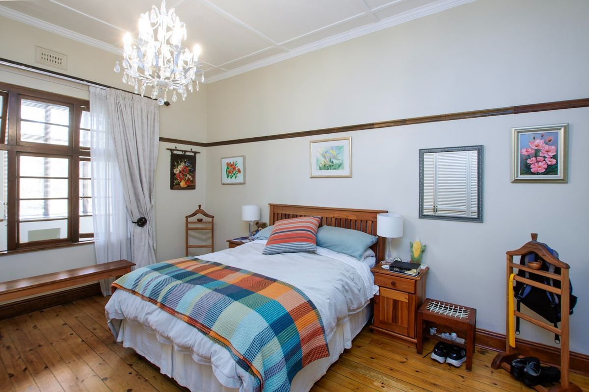A well-maintained bedroom featuring original timber flooring, classic picture rails, and a decorative ceiling rose, offering a warm and character-filled living space.