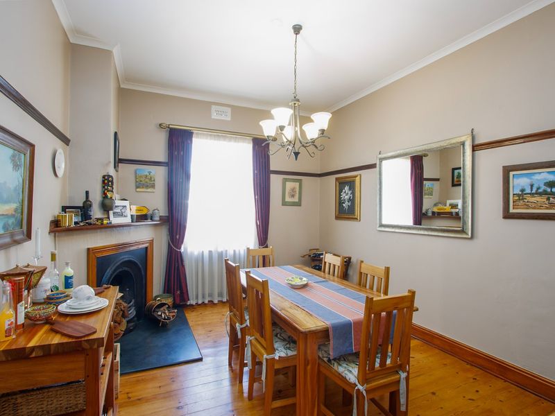 A traditional dining room featuring polished timber flooring, a classic fireplace, picture rails, and a central chandelier, creating a warm and inviting atmosphere.