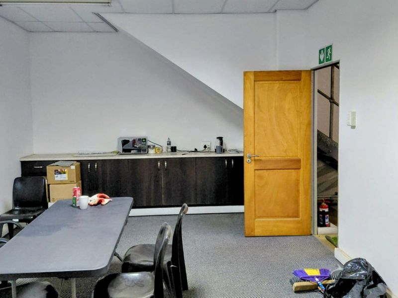Functional office space featuring built-in cabinetry, carpeted flooring, and a suspended ceiling, providing a practical workspace environment.