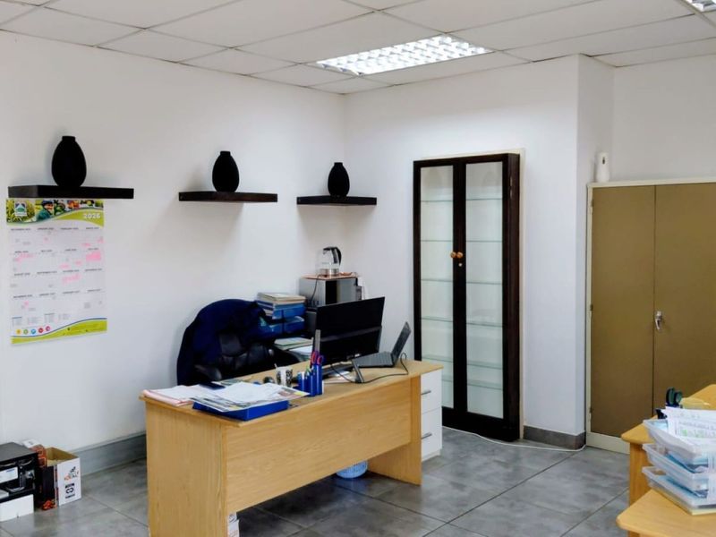 A functional office space featuring tiled flooring, a suspended ceiling with recessed lighting, and built-in storage cabinetry.