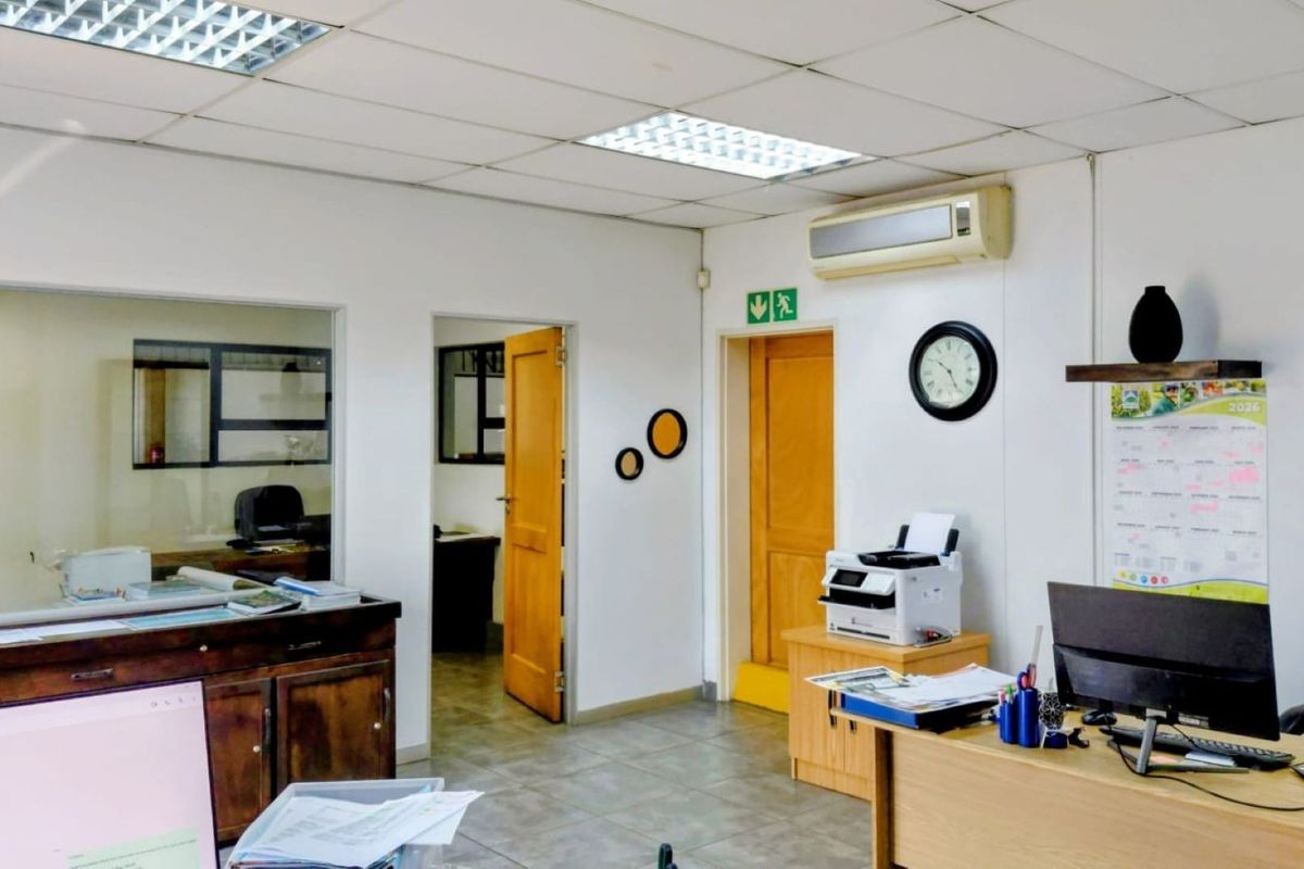 Functional office space featuring a suspended ceiling, recessed lighting, wall-mounted air conditioning, and a glass partition for visibility into adjacent areas.