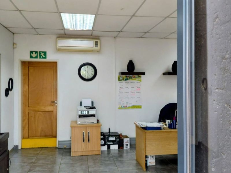 A functional office space featuring a suspended ceiling, recessed lighting, split-system air conditioning, and tiled flooring.