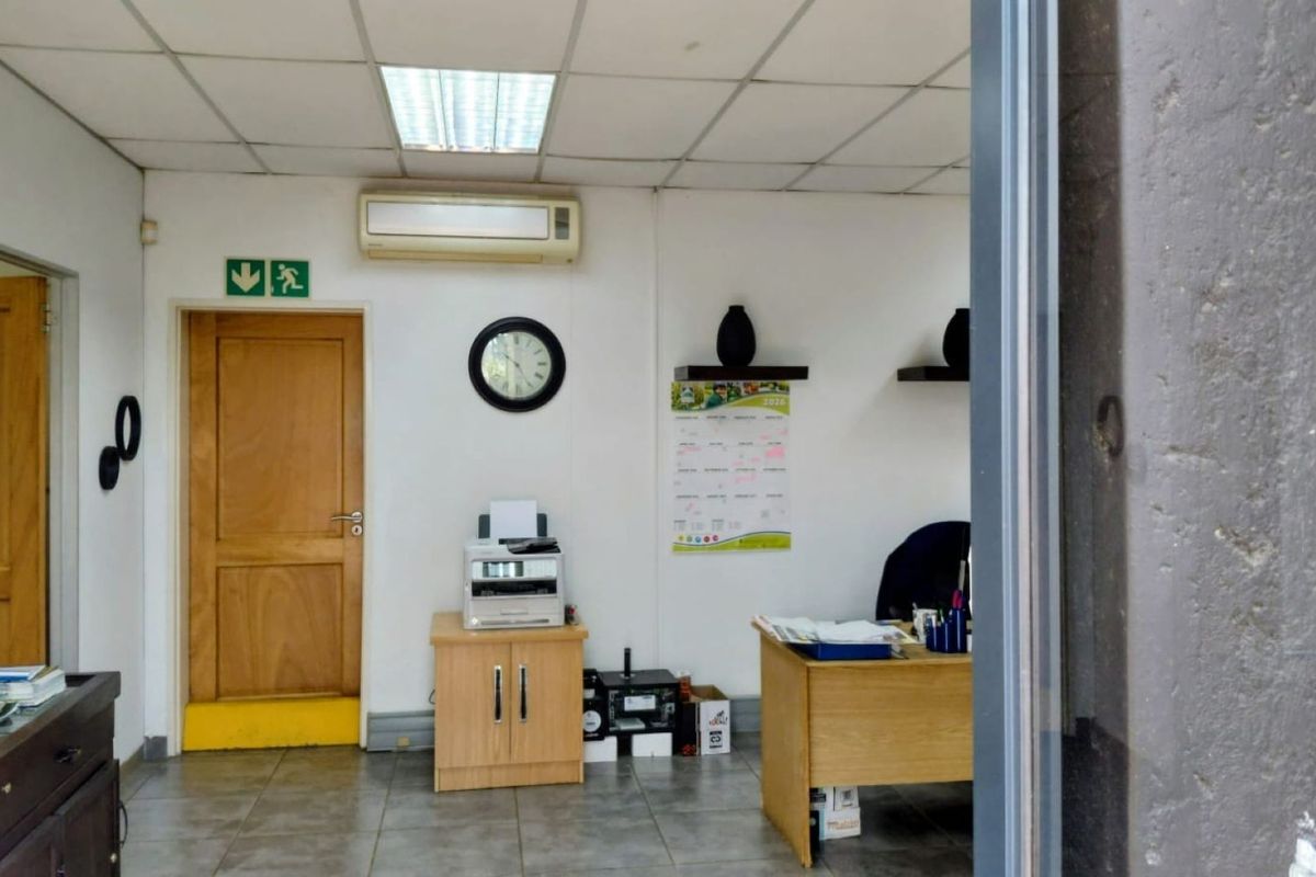 A functional office space featuring a suspended ceiling, recessed lighting, split-system air conditioning, and tiled flooring.