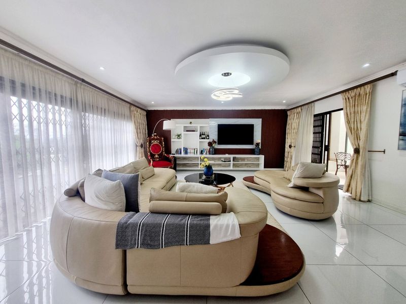 Spacious living room featuring a modern recessed ceiling design, built-in media cabinetry, and large sliding glass doors that provide ample natural light.