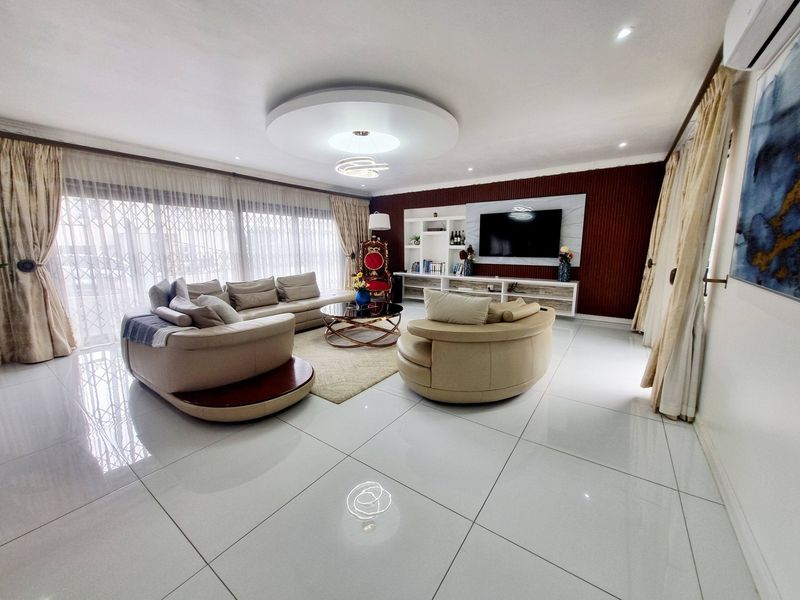 Spacious living room featuring polished porcelain floor tiles, a modern recessed ceiling design, and a custom built-in media wall unit.
