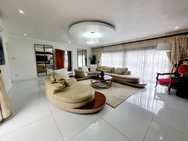 Spacious living room featuring large format tiled flooring, a decorative circular ceiling feature with recessed lighting, and expansive sliding glass doors leading outdoors.