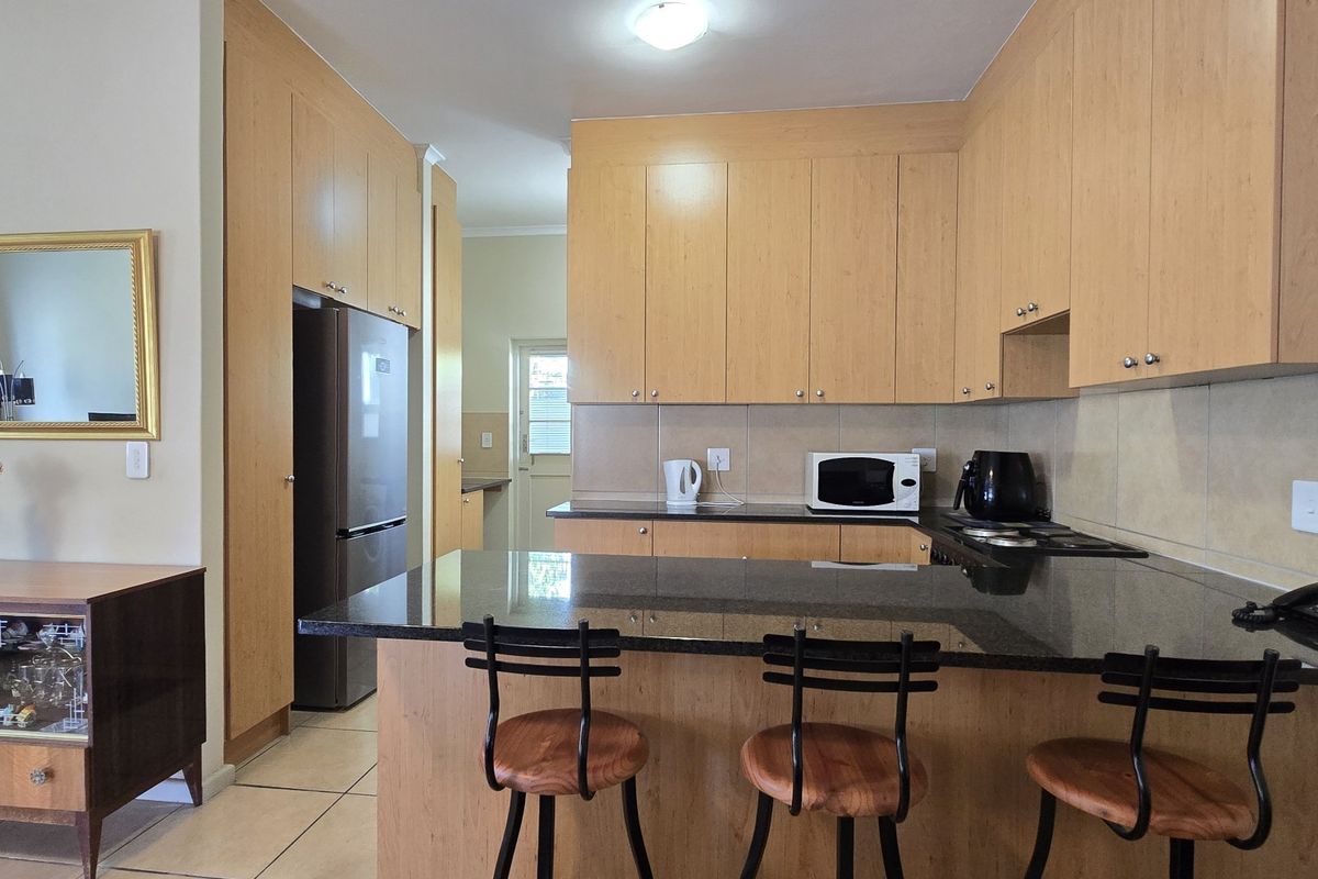 A functional kitchen featuring light wood cabinetry, granite countertops, a breakfast bar, and tiled flooring, offering a clean and practical layout.