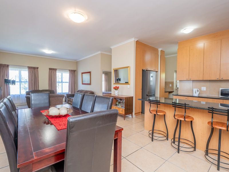 Open-plan living and dining area featuring a functional kitchen with granite countertops, breakfast bar, and tiled flooring throughout the connected space.