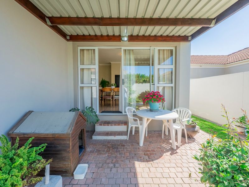 A covered patio area featuring brick paving, timber roof beams, and a sliding glass door providing access to the interior living space.