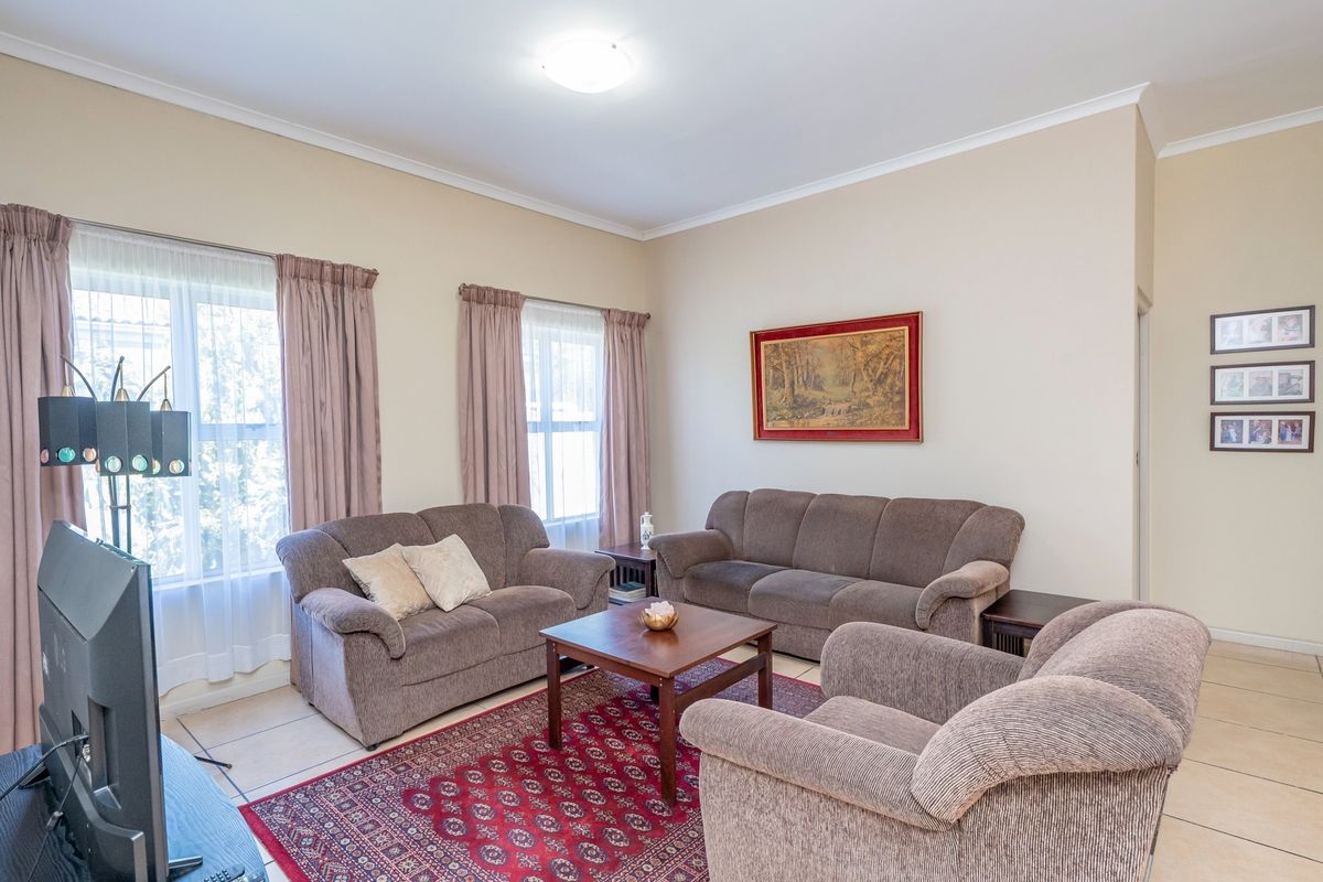 A spacious living room featuring neutral wall tones, tiled flooring, and large windows that provide ample natural light.
