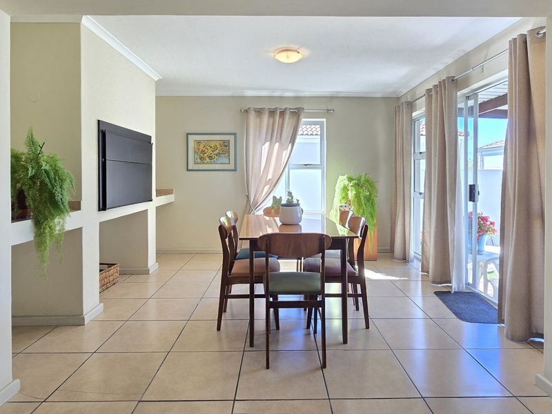 A bright dining area featuring tiled flooring, a built-in fireplace, and sliding glass doors that provide direct access to the outdoor patio.