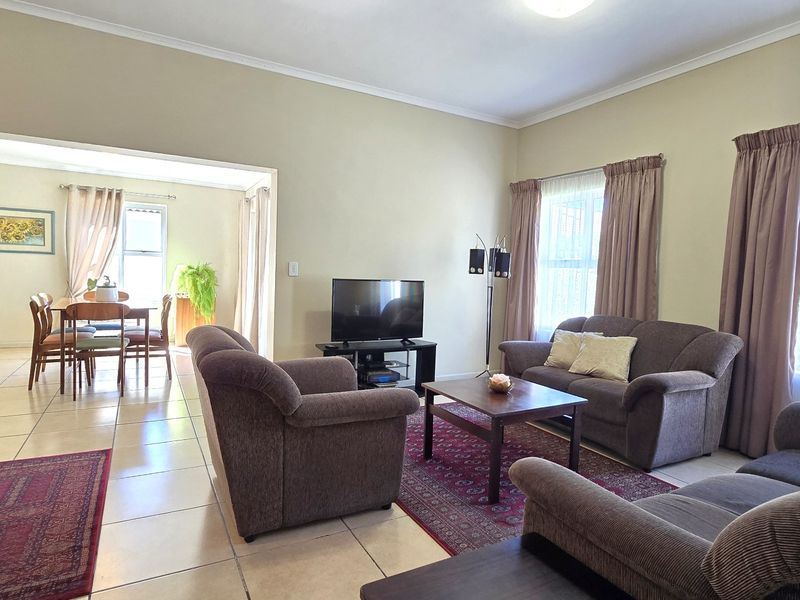 Spacious open-plan living and dining area featuring neutral wall tones, tiled flooring, and large windows that provide ample natural light.