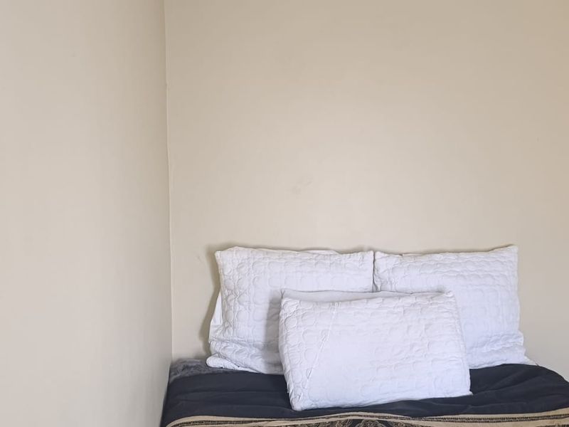 A simple bedroom corner featuring neutral wall paint and a standard electrical outlet.