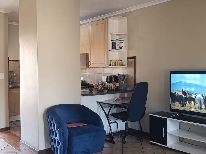 Open plan living area featuring tiled flooring and a functional kitchen with built-in cabinetry and a breakfast counter.