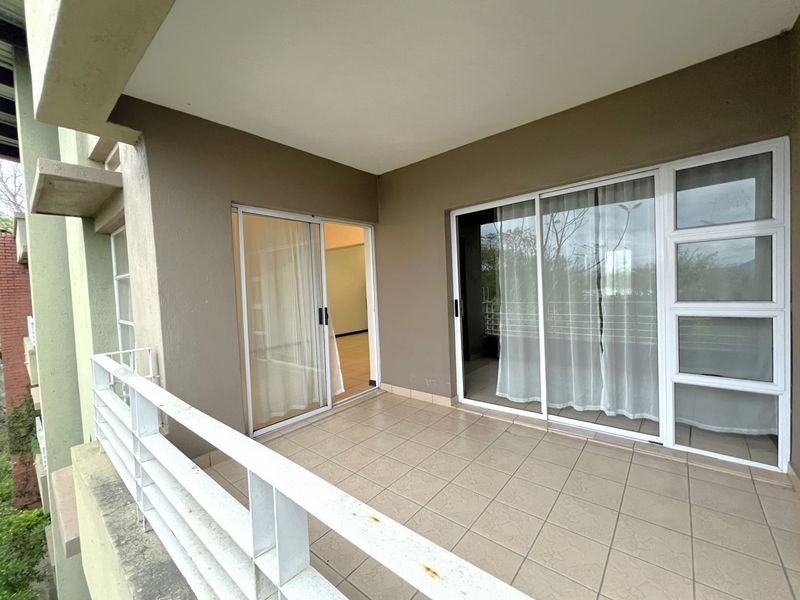 A covered balcony featuring tiled flooring, metal balustrades, and sliding glass door access to the interior living space.